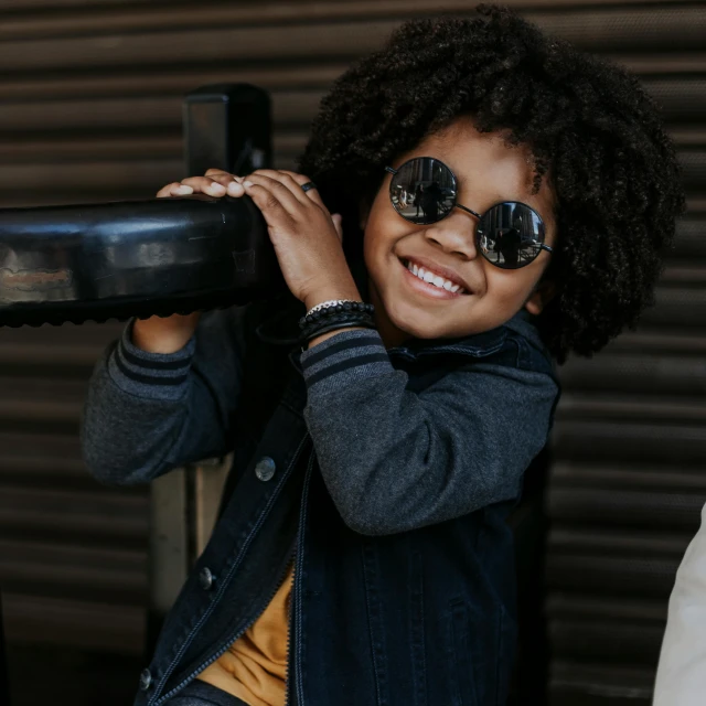 a close up of a child wearing sunglasses, pexels contest winner, afro tech, round sunglasses, black textured, kids playing