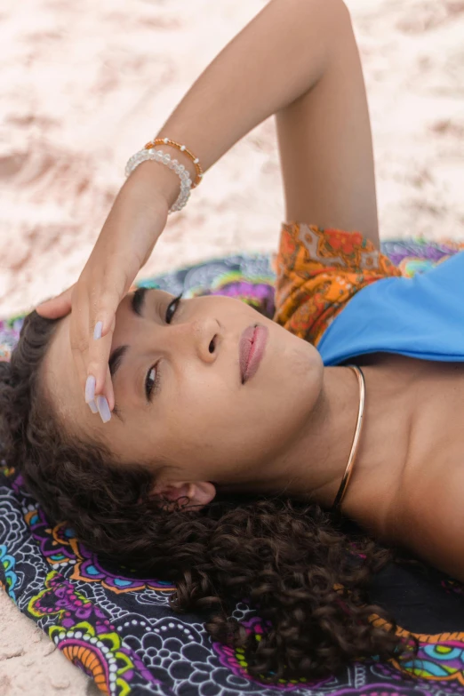 a woman laying on a towel on the beach, a portrait, trending on pexels, renaissance, jeweled ornament over forehead, light-brown skin, hands shielding face, chakra diagram face