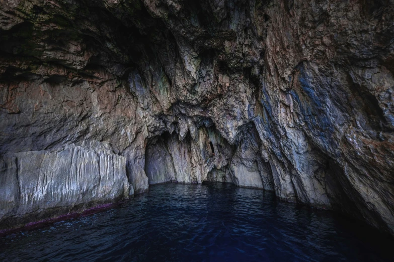 a cave in the middle of a body of water, dark blue water, thumbnail, croatian coastline, coloured