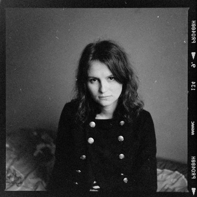 a black and white photo of a woman sitting on a bed, a black and white photo, by Lasar Segall, alternate album cover, cute girl, hermione, cash