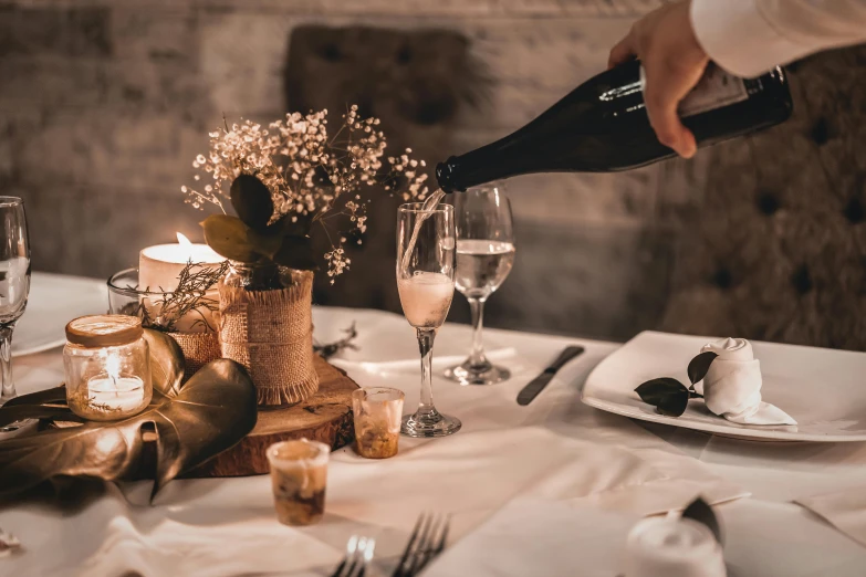 a person pouring wine into a glass on a table, by Daniel Lieske, pexels contest winner, renaissance, place setting, rustic, bubbly, creamy