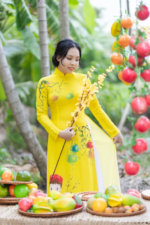 a woman in a yellow dress standing next to baskets of fruit, inspired by Jin Nong, ao dai, on a branch, 15081959 21121991 01012000 4k, vibrant aesthetic