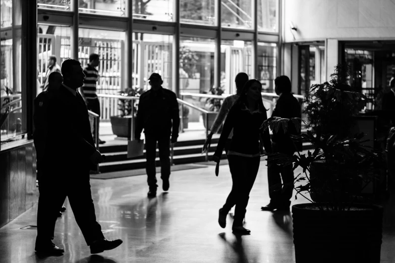 a group of people walking down a hallway, a black and white photo, by Tobias Stimmer, pexels, people at work, atrium, summer evening, promo image