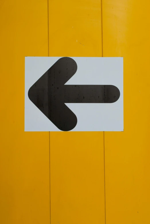 a black and white arrow sign on a yellow wall, by Sven Erixson, integration, panel, door, floating