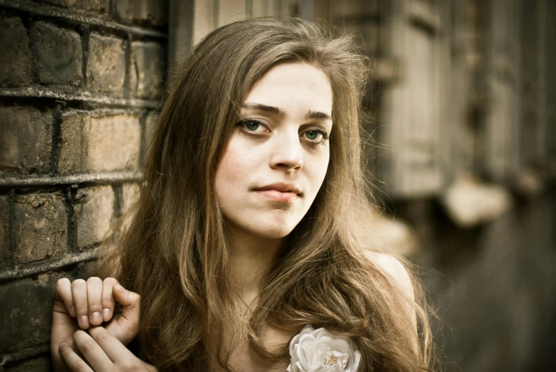 a young woman leaning against a brick wall, an album cover, inspired by Anka Zhuravleva, flickr, renaissance, beautiful huge eyes, natalia dyer, sigma 85/1.2 portrait, girl with long hair