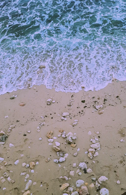 a white surfboard sitting on top of a sandy beach, ((rocks)), drone view, lo fi, rippling muscles