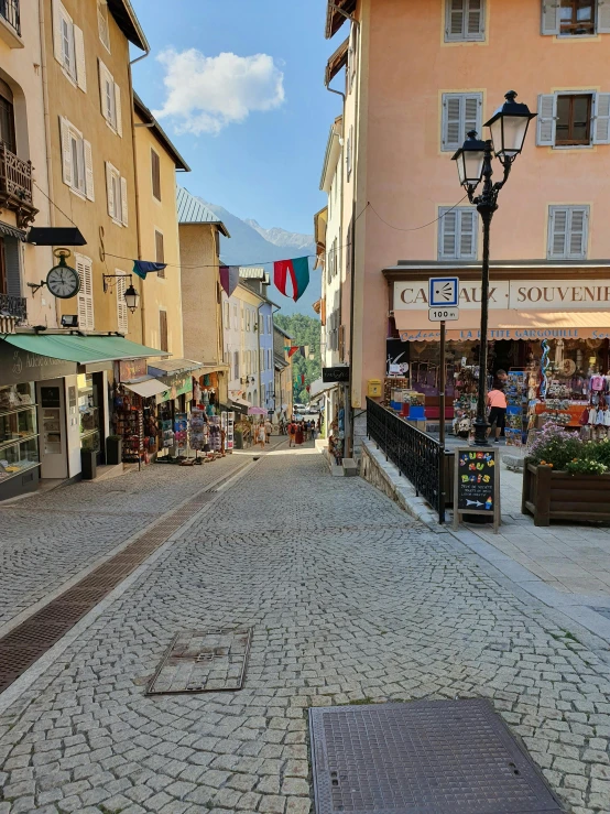 a street filled with lots of shops next to tall buildings, les nabis, dolomites in background, square, french village interior, photograph taken in 2 0 2 0