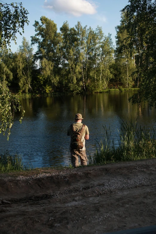 a man standing next to a body of water, fishing, rutkowskyi, lush surroundings, commercially ready