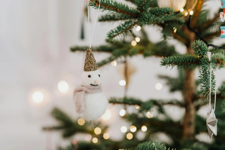 a snowman ornament hanging from a christmas tree, a portrait, pexels contest winner, fluffy full of light, scandinavian style, astri lohne, miniature product photo