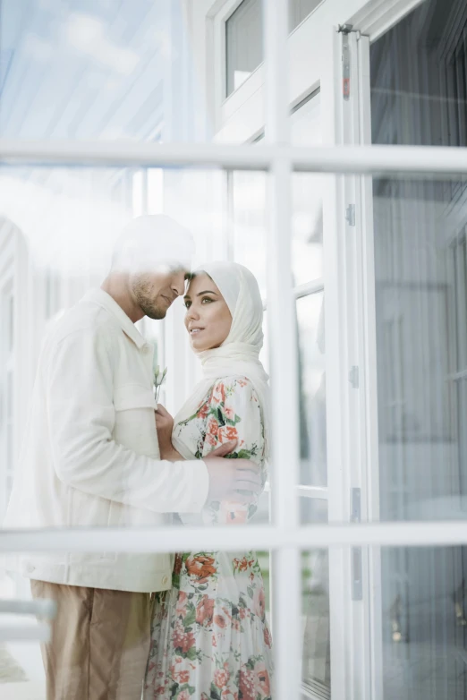 a man and a woman standing next to each other, pexels contest winner, hurufiyya, near a window, white hijab, square, swedish