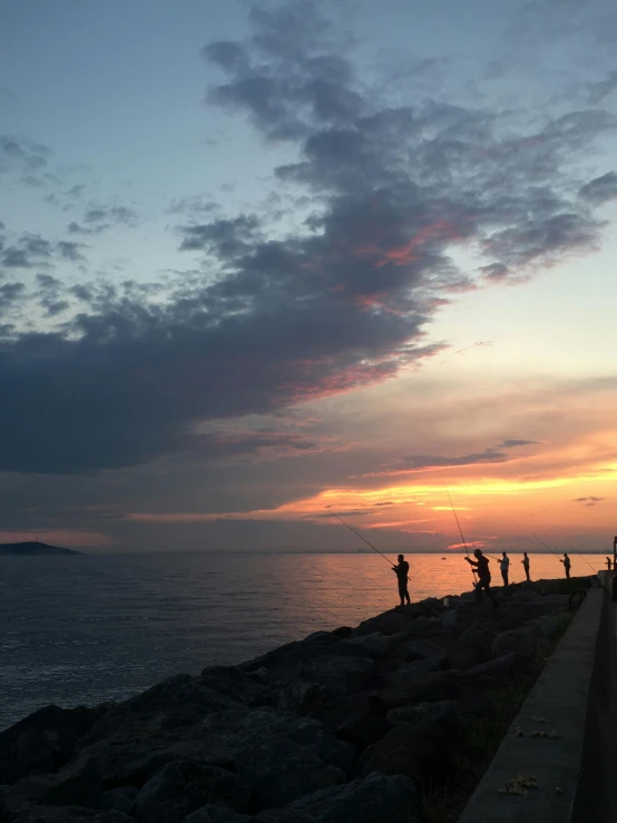 a group of people standing on top of a pier next to the ocean, fishing pole, in the evening, # nofilter, naples