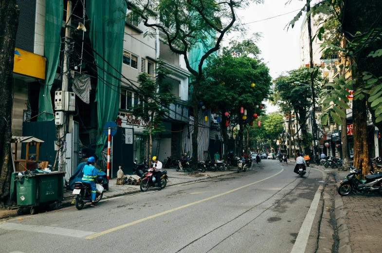 a group of people riding motorcycles down a street, a photo, pexels contest winner, outdoors tropical cityscape, square, hoang lap, quiet street