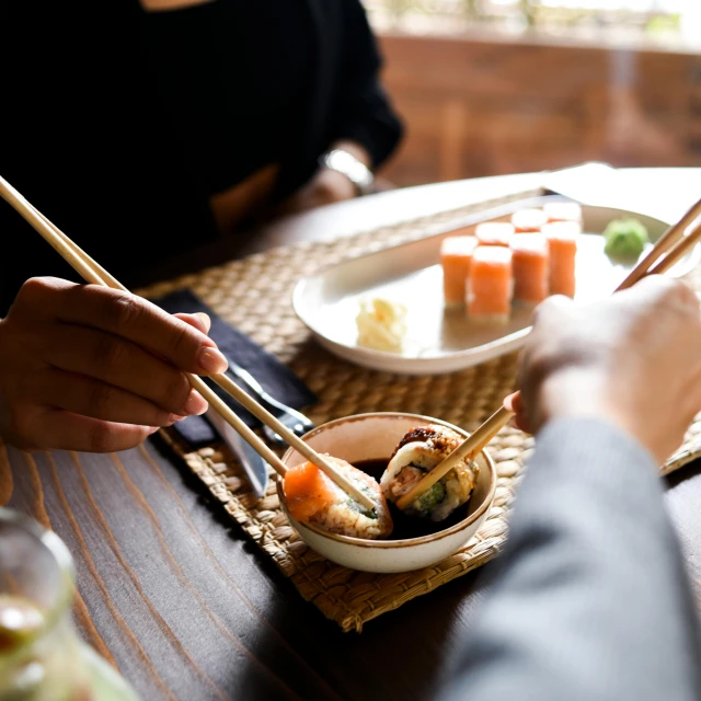 a person eating sushi with chopsticks at a table, having an awkward dinner date, winter sun, michelin starred restaurant, people inside eating meals