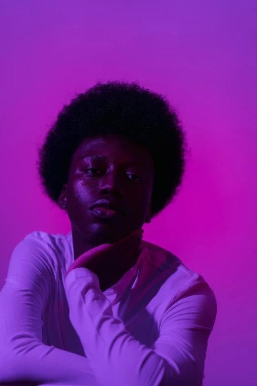 a man sitting in front of a purple background, pexels contest winner, black arts movement, colored gel lighting, black teenage boy, curls on top of his head, ( ( dark skin ) )