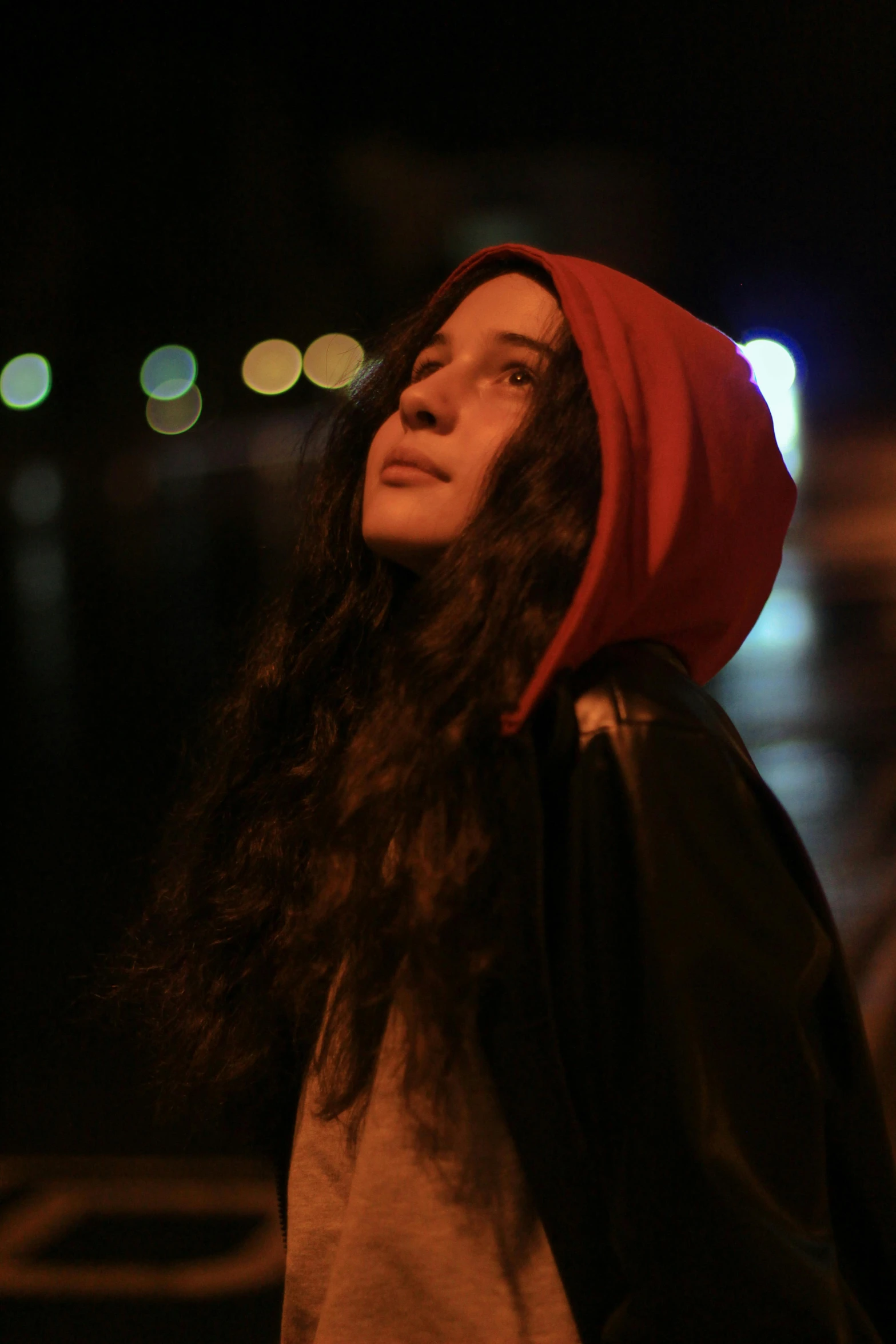 a woman standing on a city street at night, an album cover, pexels contest winner, renaissance, red cap, young woman with long dark hair, ( ( theatrical ) ), icon