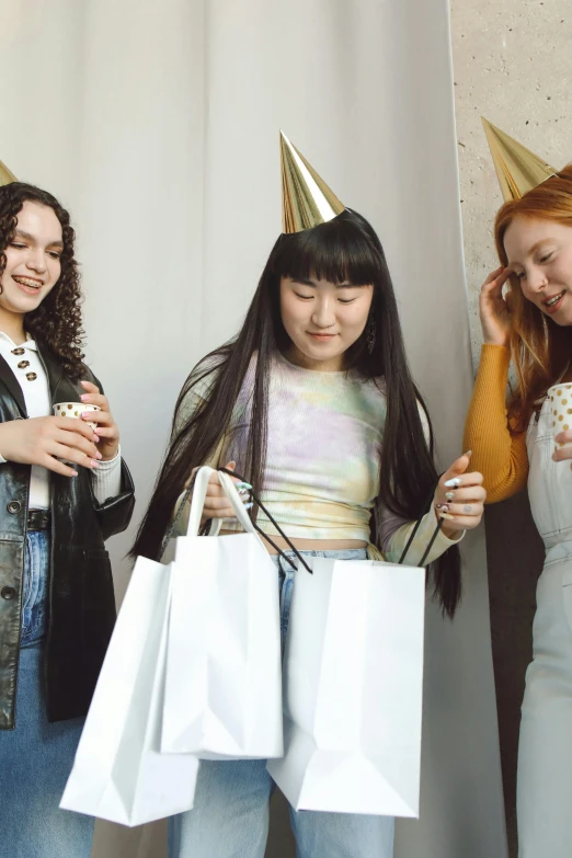 a group of women standing next to each other holding shopping bags, an album cover, by Julia Pishtar, trending on pexels, happening, party hats, portrait of a japanese teen, at a birthday party, panoramic view of girl