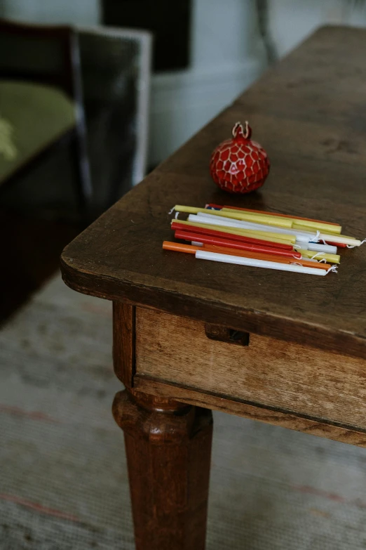 a wooden table topped with books and pencils, a child's drawing, pexels, arts and crafts movement, olive green and venetian red, loundraw, apple, french provincial furniture