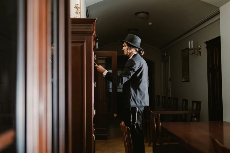 a man that is standing in a room, by Emma Andijewska, pexels contest winner, arts and crafts movement, detective, cupboards, black tie, thumbnail