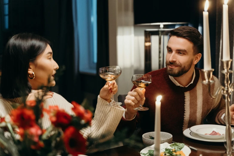 a couple of people that are sitting at a table, holding glass of wine, profile image, holding a candle holder, lifestyle