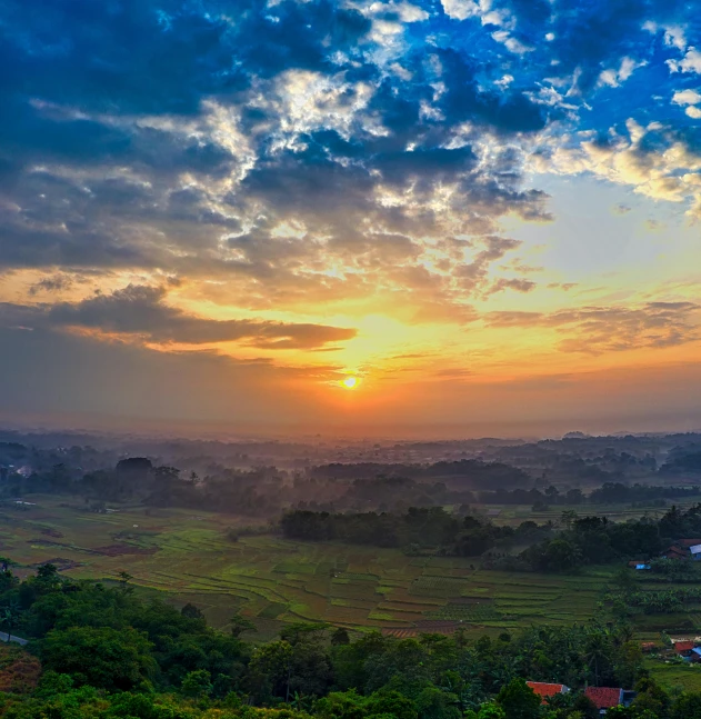 the sun is setting over a lush green valley, pexels contest winner, sumatraism, orange and blue sky, kerala village, slide show, grey