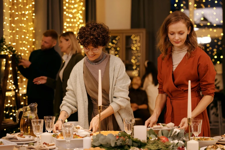 a couple of women standing next to each other at a table, by Emma Andijewska, pexels contest winner, happening, festive, dinner is served, gif, promotional image