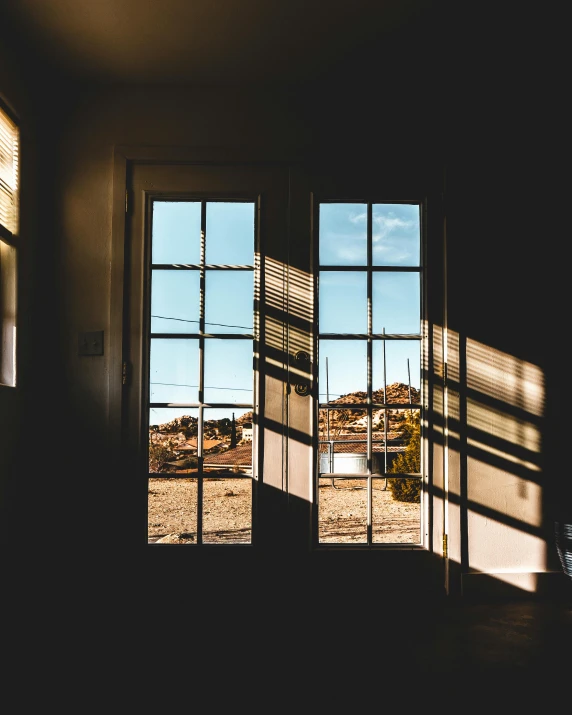 the sun shines through a window in a dark room, unsplash contest winner, big french door window, sunlight and whimsical houses, on a sunny day, taken in the late 2010s