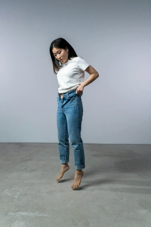 a woman standing on top of a cement floor, by Robbie Trevino, trending on unsplash, hyperrealism, white shirt and blue jeans, 1990's sears portrait photo, young asian woman, dynamic pose full body