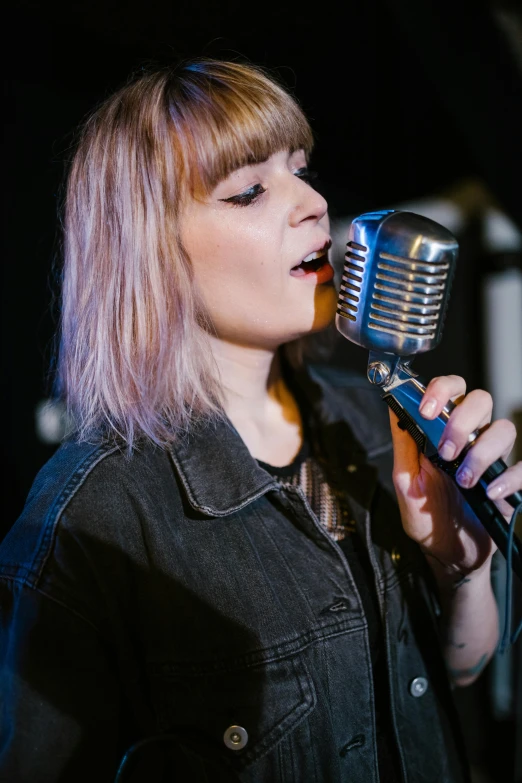 a woman singing into a microphone on a stage, an album cover, pexels, realism, with a fringe, lookalike, studio, pastel'