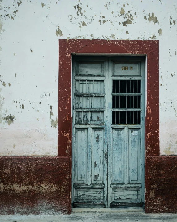 a red and white building with a blue door, by Elsa Bleda, pexels contest winner, 1 8 th century south america, weathered olive skin, square, faded chipped paint