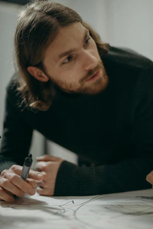 a man sitting at a table writing on a piece of paper, mid long hair, designer product, multiple stories, christian