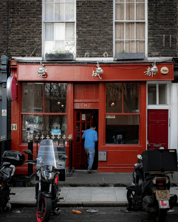 a couple of motorcycles parked in front of a building, by Nick Fudge, pexels contest winner, private press, chinatown bar, doorway, a red cape, panoramic shot