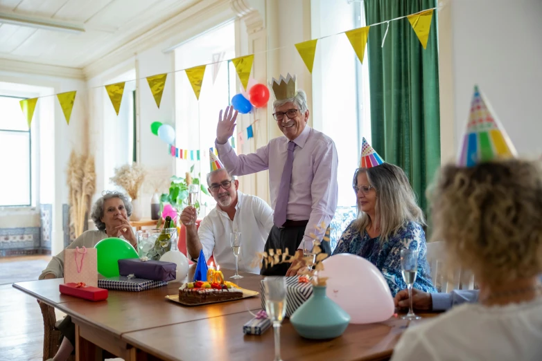 a group of people sitting around a wooden table, by Alison Debenham, pexels contest winner, wearing a party hat, he is about 7 0 years old, decorations, avatar image