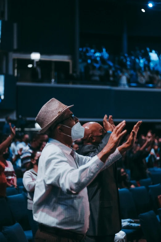 a man standing in front of a crowd of people, pray, masks, trending on gc society, people enjoying the show