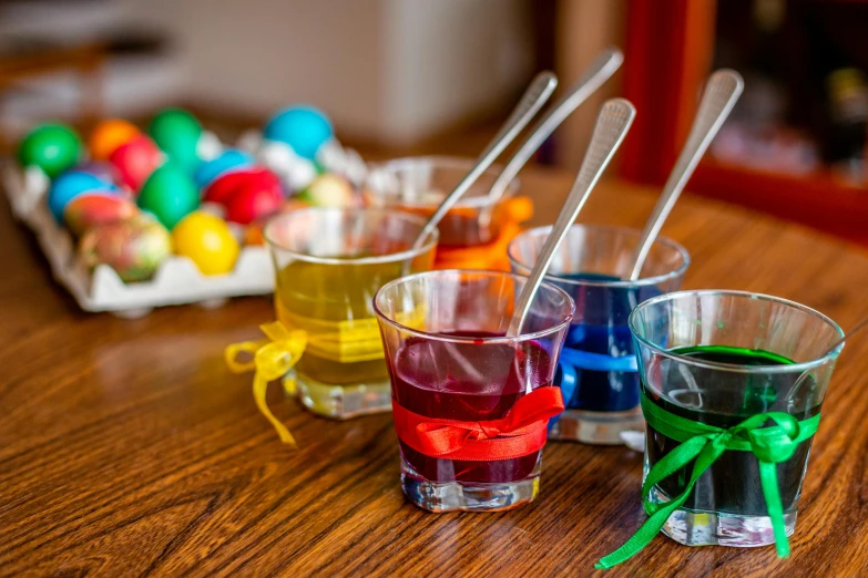 a wooden table topped with three shot glasses filled with colored liquid, inspired by Albert Joseph Pénot, pexels, holding easter eggs, holding paintbrushes, avatar image, cups and balls