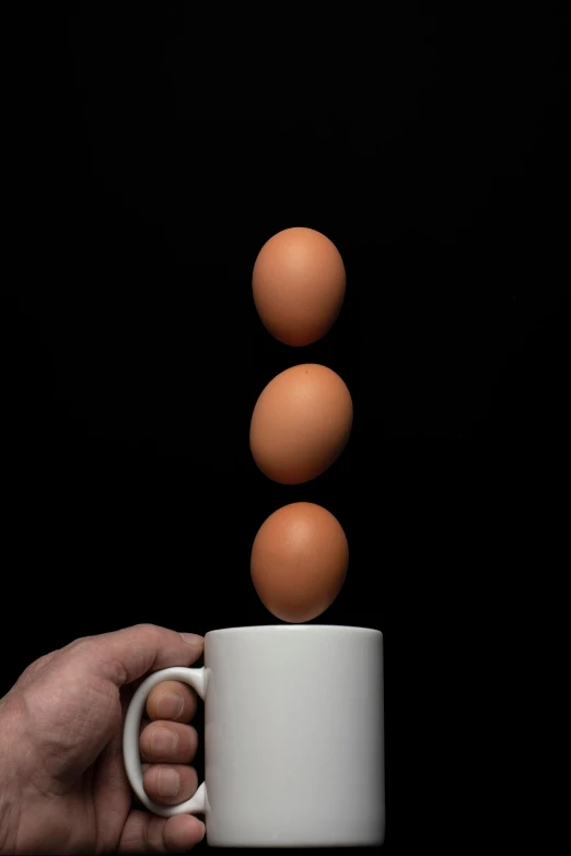 a person holding a coffee cup with three eggs coming out of it, by Matthias Stom, unsplash, hyperrealism, portrait of tall, with a black background, cuastics, at a slightly elevated level