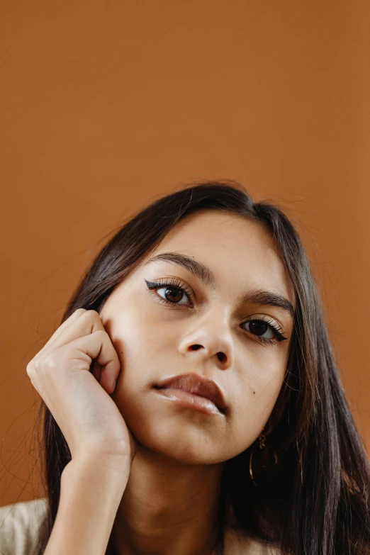 a beautiful young woman posing for a picture, an album cover, trending on pexels, realism, indian girl with brown skin, solid background, raised eyebrow, close-up portrait film still