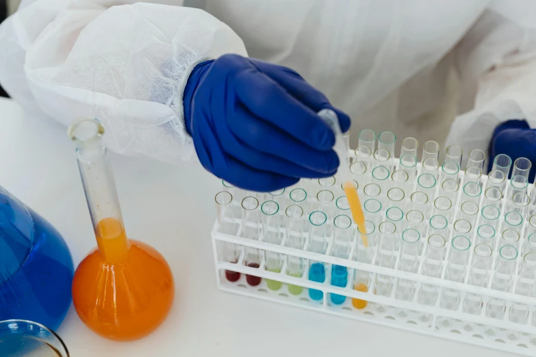 a person in a lab coat holding a tube filled with liquid, pexels, some orange and blue, contracept, yellow latex gloves, gif