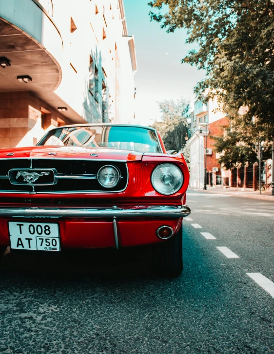 a red mustang parked on the side of the road, trending on unsplash, in a city with a rich history, 🚿🗝📝, vsco, instagram post