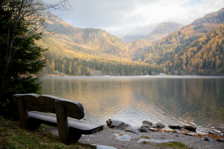a wooden bench sitting next to a body of water, pexels contest winner, autumn mountains, fan favorite, late afternoon, alpine scenery
