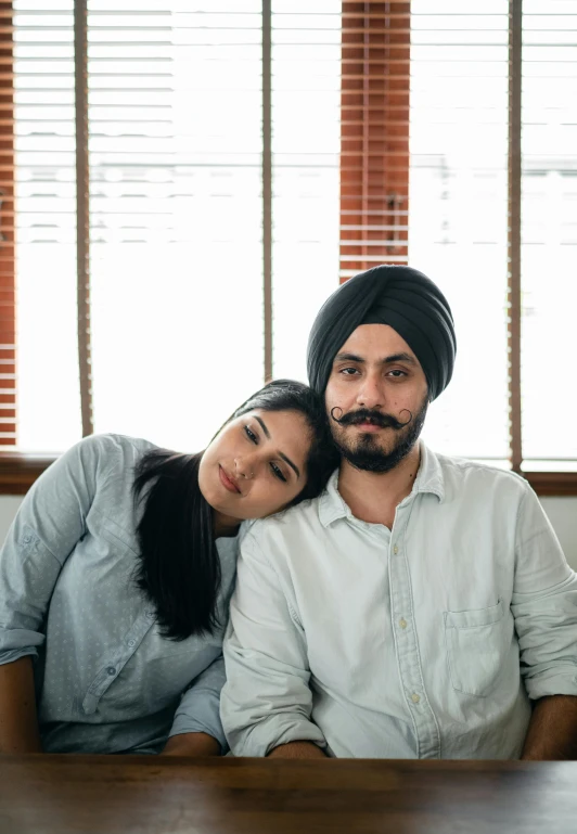 a man and a woman sitting next to each other, a portrait, by Manjit Bawa, trending on unsplash, two buddies sitting in a room, turban, arm around her neck, promotional image