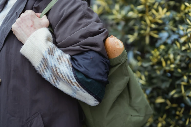 a close up of a person holding a baguet, inspired by Sarah Lucas, unsplash, people on a picnic, detached sleeves, carrying big sack, two men hugging