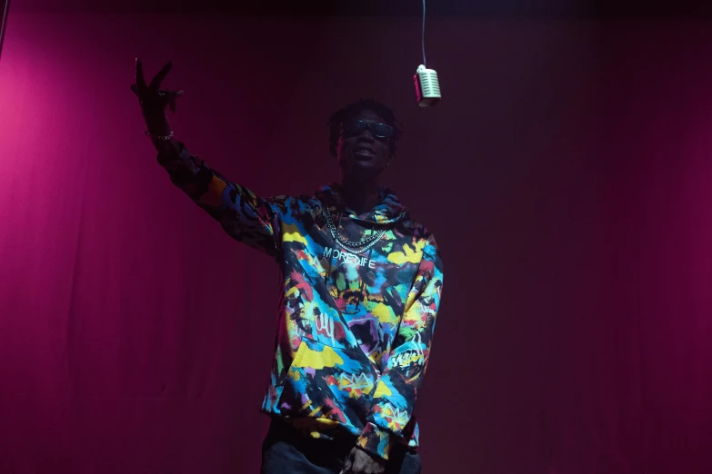 a man standing on top of a stage, an album cover, unsplash, young thug, shot with a camera flash, ( ( theatrical ) ), multi colored