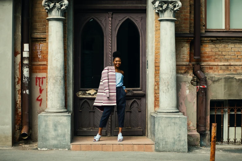 a woman standing in the doorway of a building, by Nina Hamnett, pexels contest winner, wearing adidas clothing, lupita nyong'o, stripes, james jean andrei riabovitchev