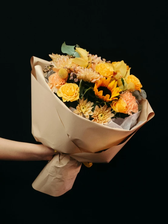 a person holding a bouquet of yellow and orange flowers, inspired by François Boquet, unsplash, on black background, wrapped, 🍂 cute, full product shot