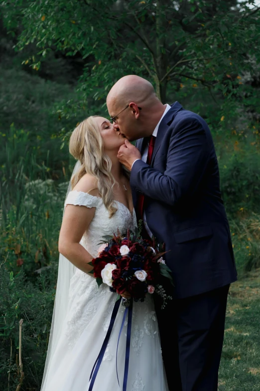 a bride and groom kissing in a field, maroon and blue accents, video, bald, paul barson