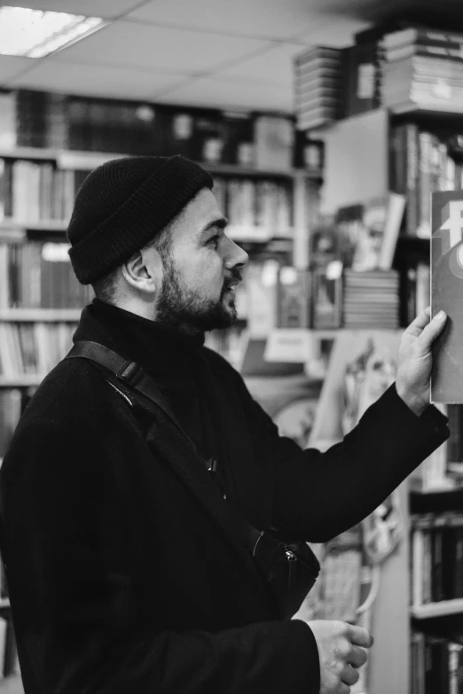 a man reading a book in a library, a black and white photo, art & language, wearing a french beret, jeffrey wright, demna gvasalia, promo image