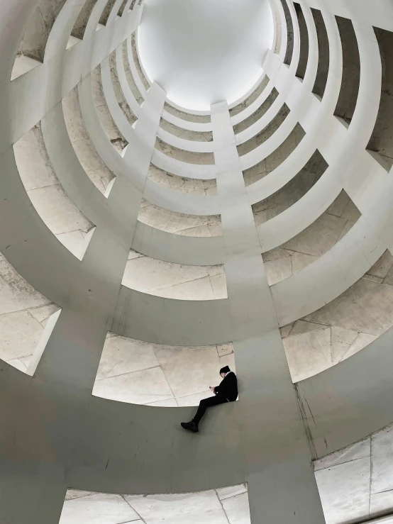 a man sitting in the middle of a circular building, inspired by Kay Sage, unsplash contest winner, white spiral horns, looking up, peter eisenman, instagram story