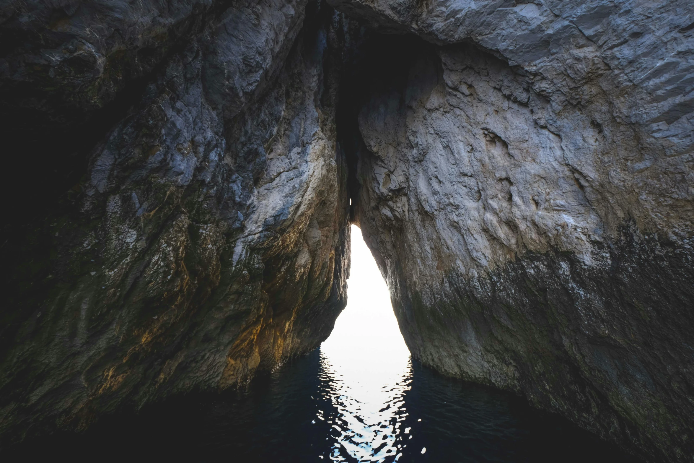 a cave in the middle of a body of water, dark warm light, capri coast, doorway, head straight down