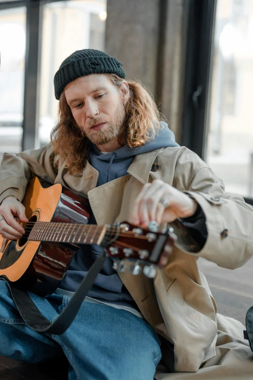 a man sitting on a couch playing a guitar, trending on pexels, renaissance, medium long wavy ginger hair, on a street, sad man, australian