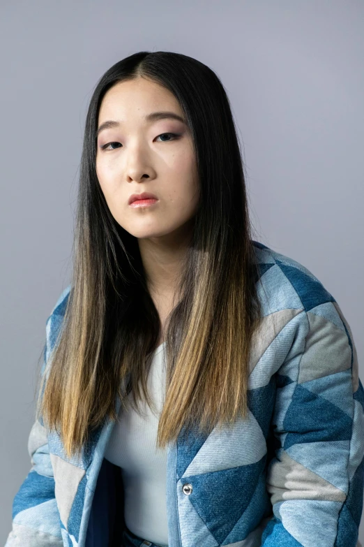 a woman sitting down with a remote control in her hand, inspired by Kim Tschang Yeul, unsplash, hyperrealism, acting headshot, model wears a puffer jacket, in front of white back drop, standing